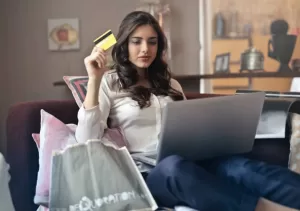Woman sitting down with a laptop and credit card in hand