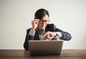 Confused businessman checking the time on his wrist watch